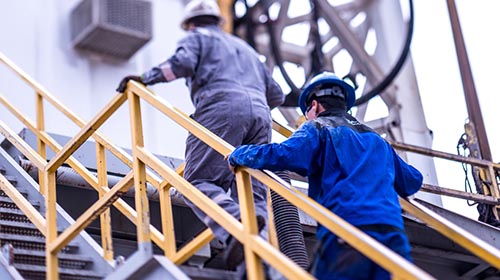 oil refinery workers walking up stairs outside